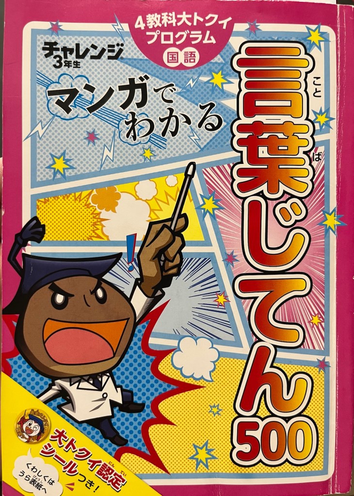 The cover of a textbook with Japanese written on it, where kids can learn 500 words using fun manga illustrations. The front cover features a cartoon character with a professor hat.