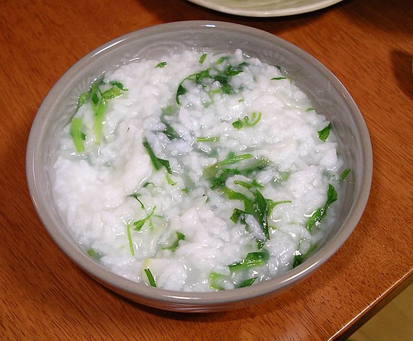 A small bowl of rice porridge with various greens mixed in.